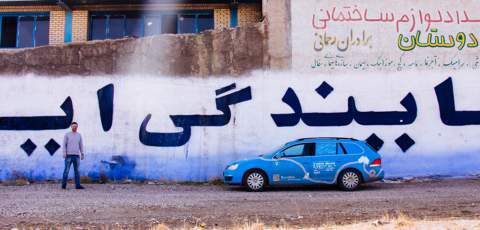 Parked beside a wall with Persian writing on it