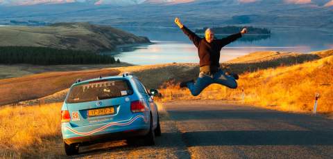 Wiebe jumping by his car infront of Lake Tekapo in New Zealand