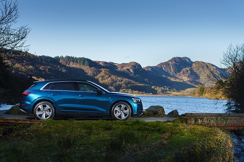 Side view on a blue Audi e-tron on a hilly background