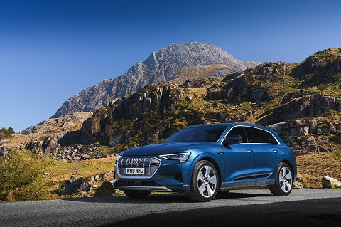 Exterior front passenger-side view of a blue Audi e-tron on a hilly background